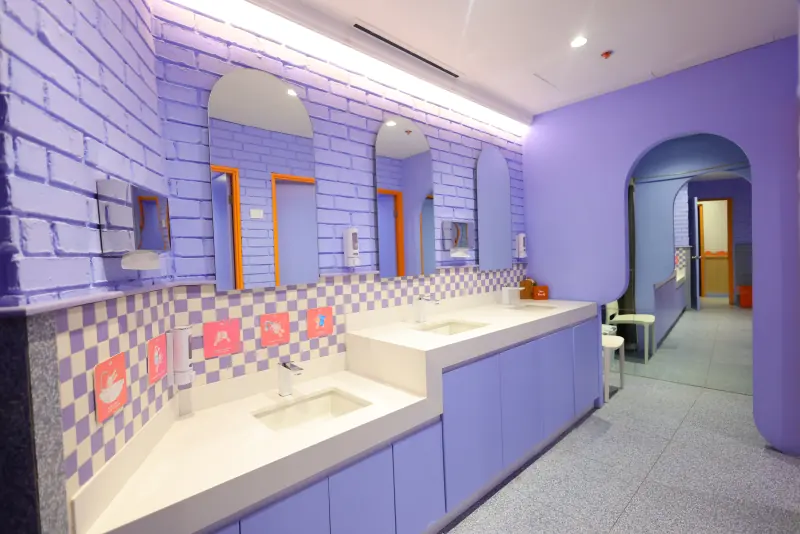 Baños con lavabos a dos alturas y paredes moradas